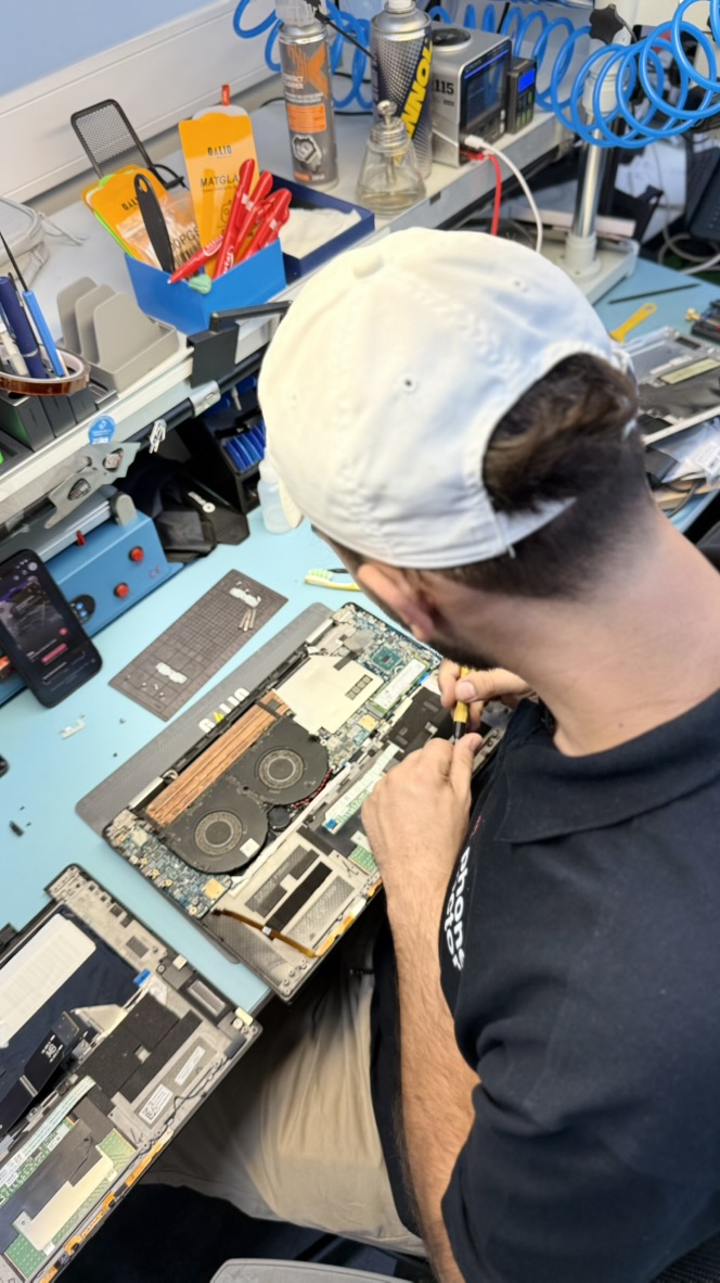 Mitarbeiter prüft die Bauteile eines geöffneten Laptops in der Phone-Doctor-Werkstatt
